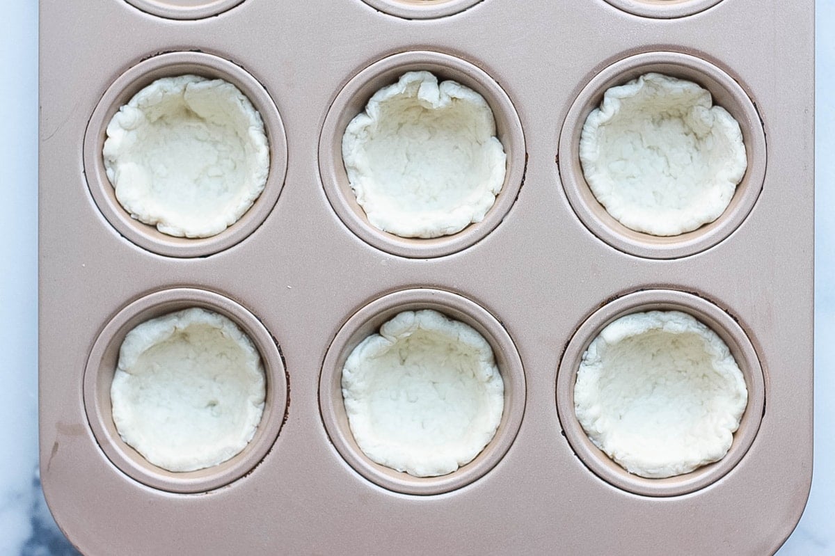 biscuit dough pressed into a muffin tin 
