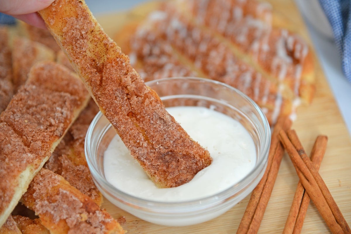 cinna stick dipping into powdered sugar icing 