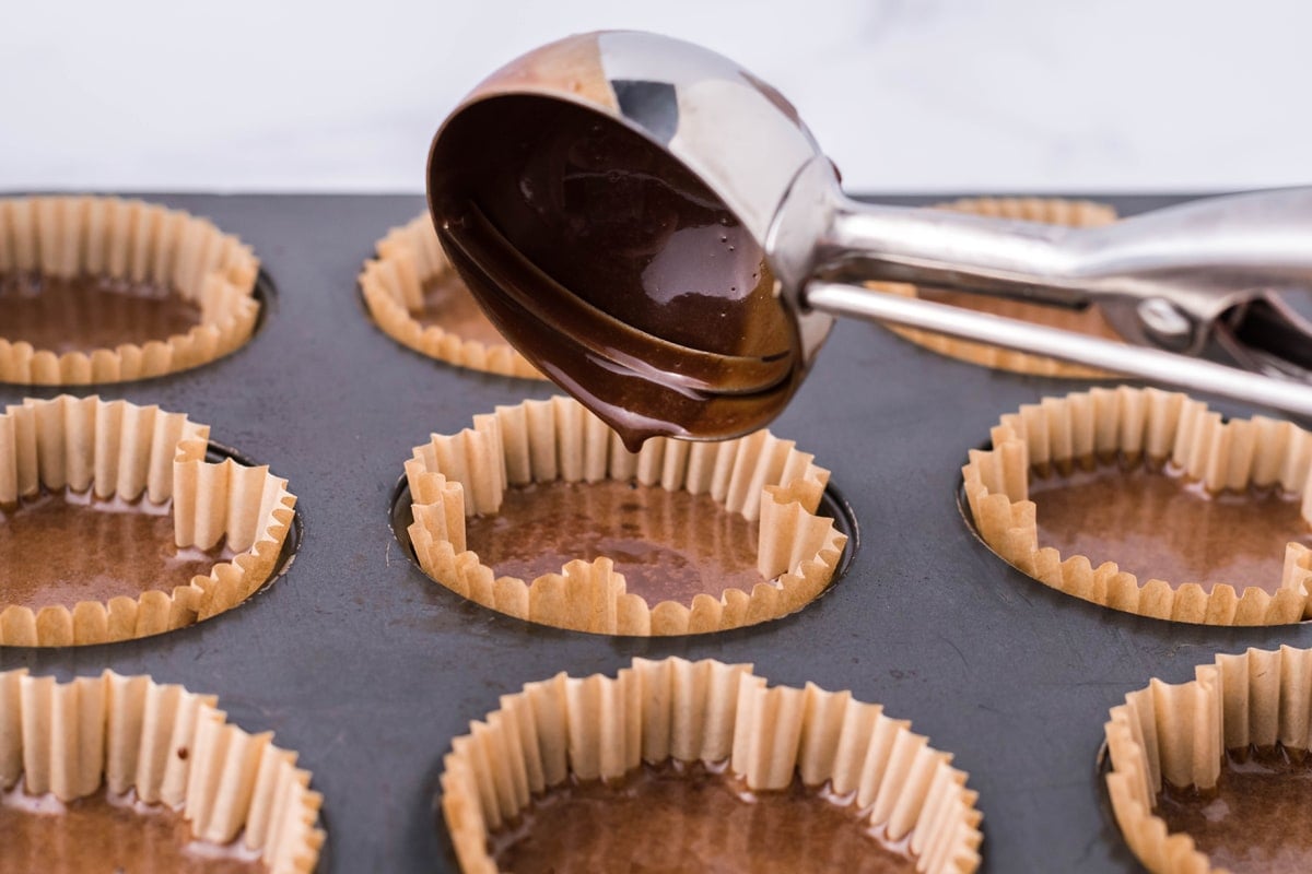 scoop filling cupcake liners with chocolate cake batter 