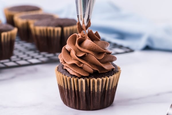 piping frosting onto a cupcake