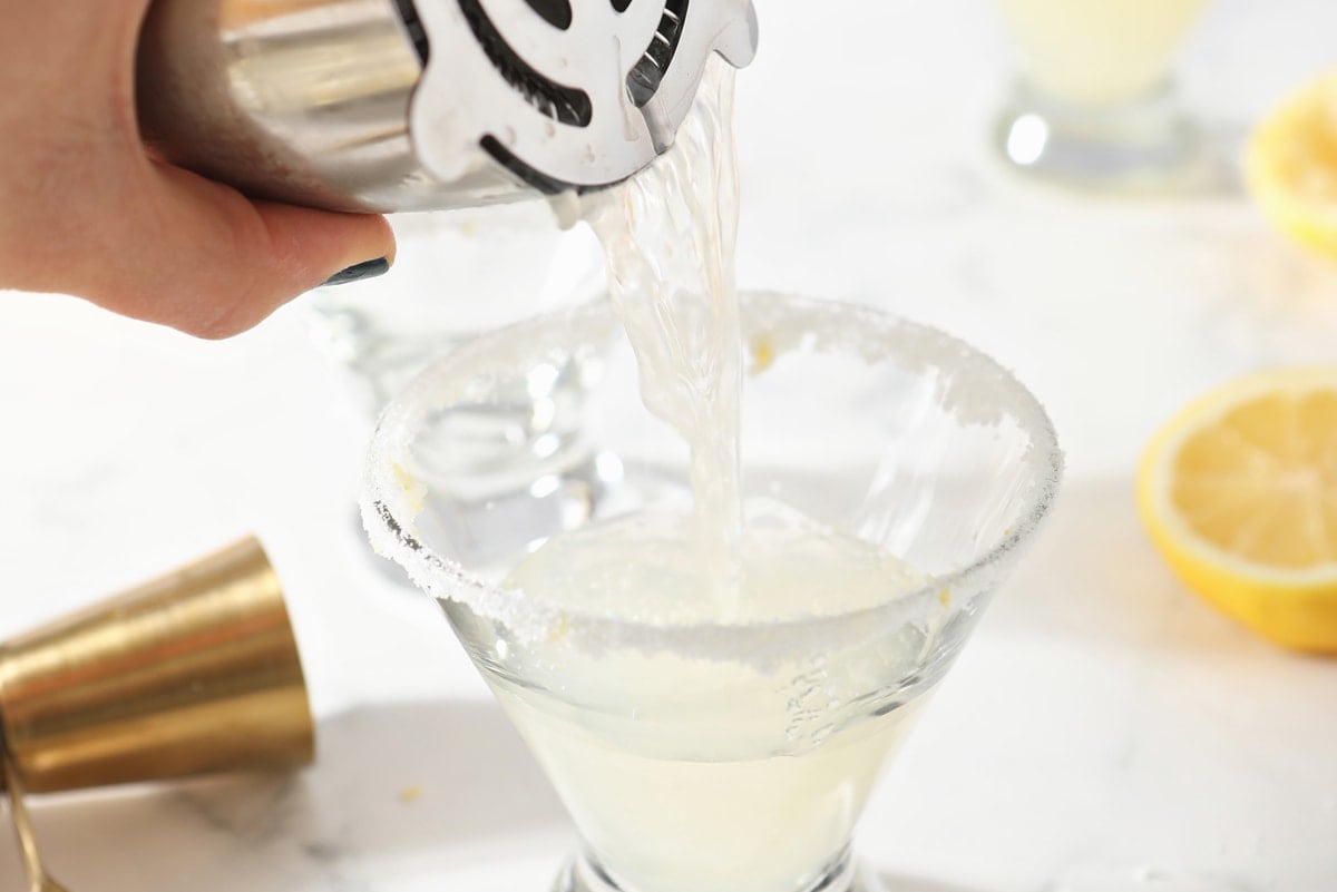 pouring lemon drop drink recipe into a glass 