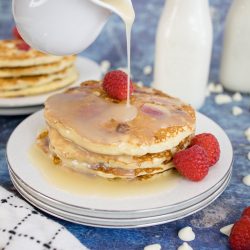 syrup pouring over a stack of raspberry pancakes