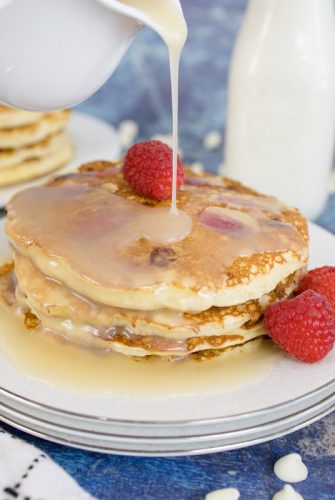 syrup pouring over a stack of raspberry pancakes