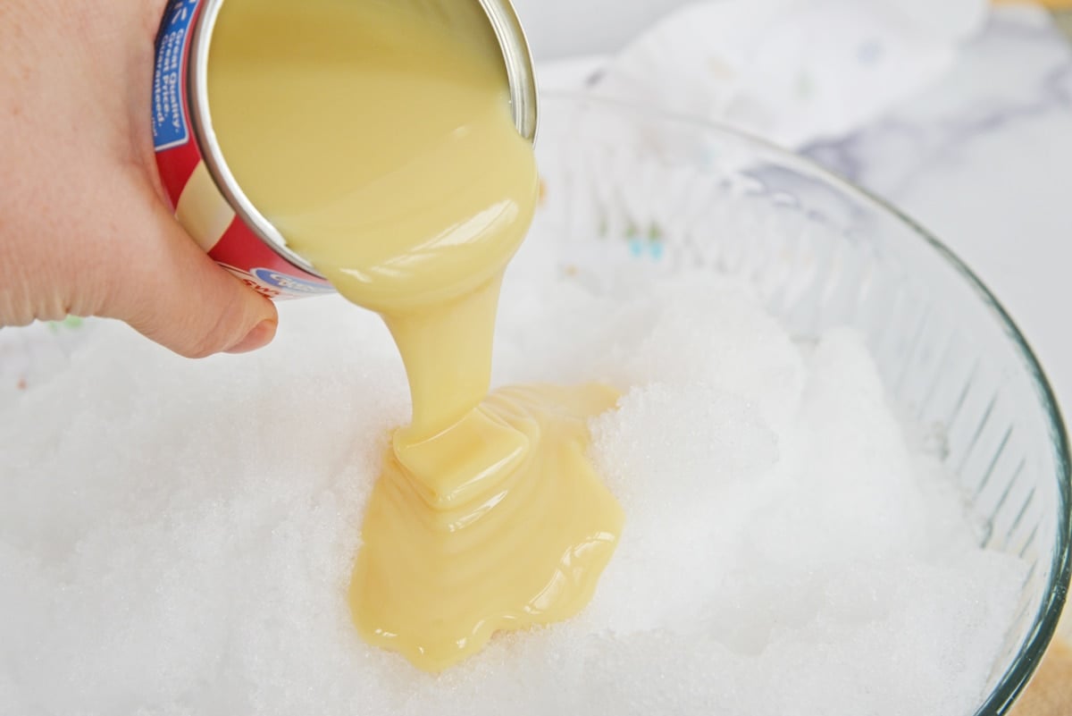 pouring sweetened condensed milk over fresh snow 