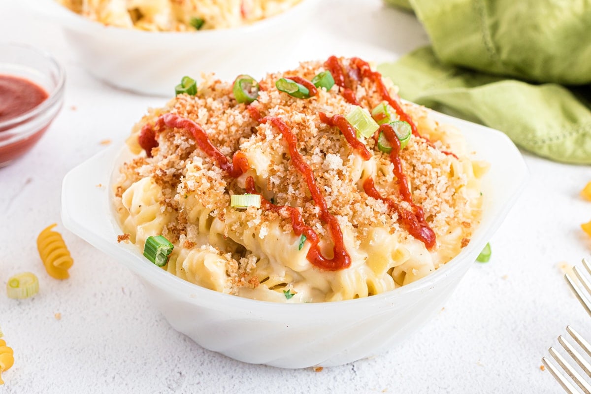 angle view of gouda mac and cheese topped with sriracha, scallions and bread crumbs 