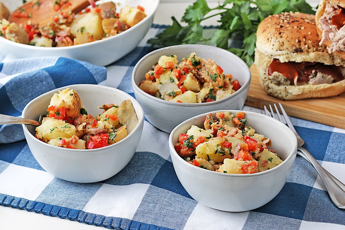 three small white bowls with bacon potato salad in them 