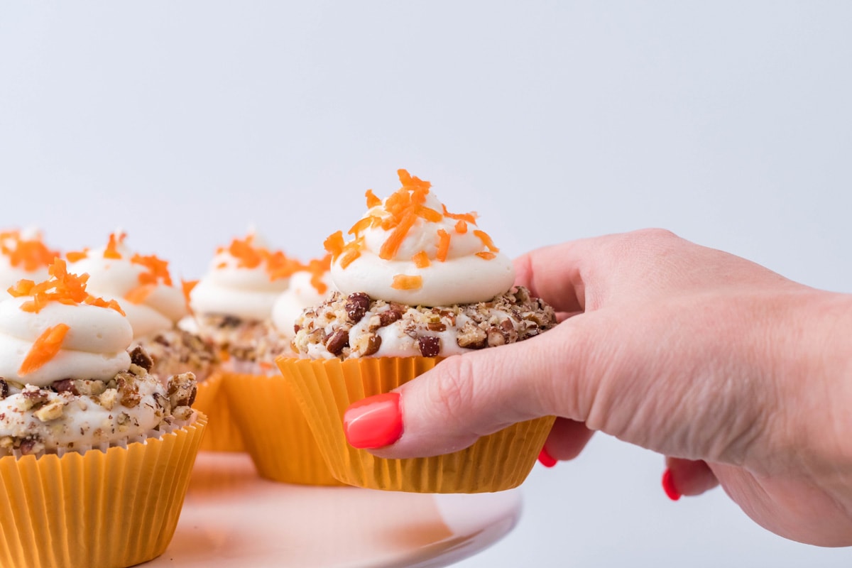 hand taking a cupcake off serving platter 