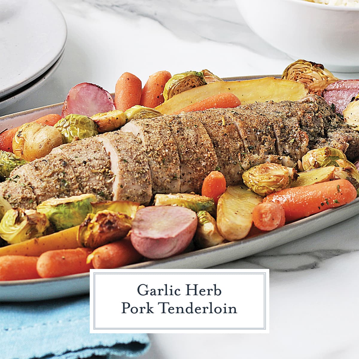 pork tenderloin on a serving platter surrounded by vegetables 