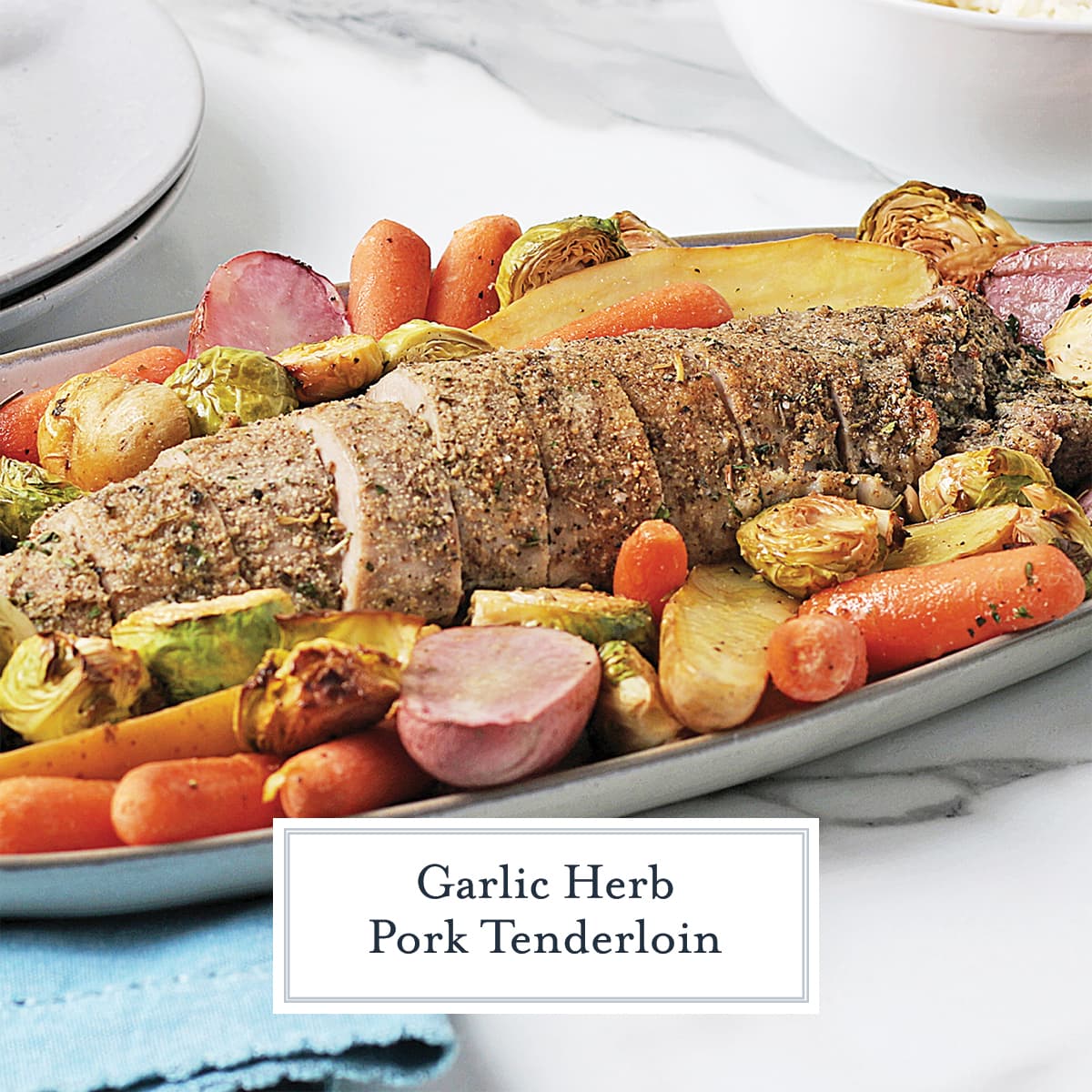 pork tenderloin on a serving platter surrounded by vegetables