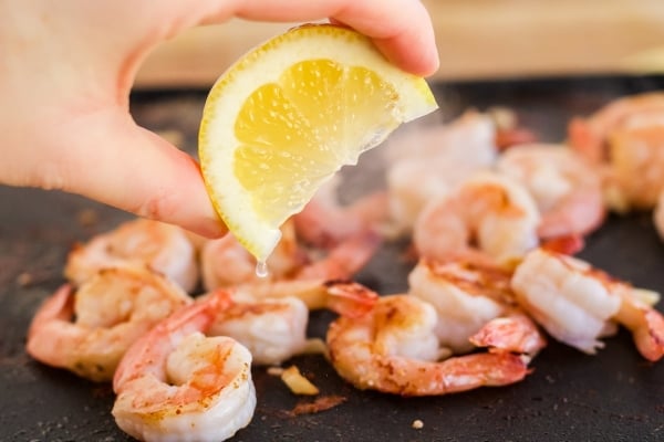 hand spritzing lemon onto shrimp