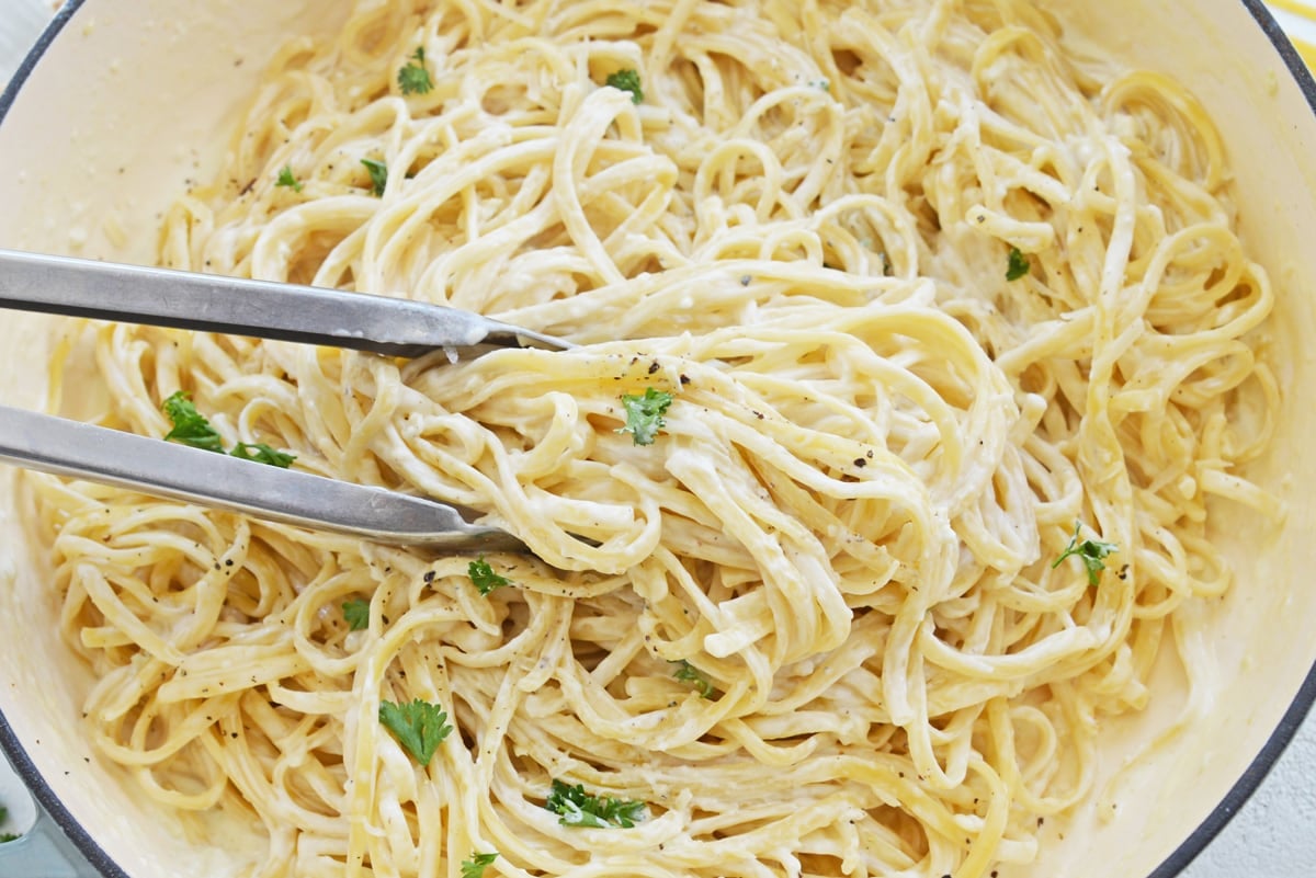 tongs tossing a creamy linguine recipe 