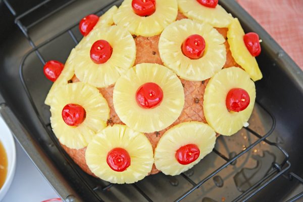 pineapple slices and cherries secured into a ham with toothpicks