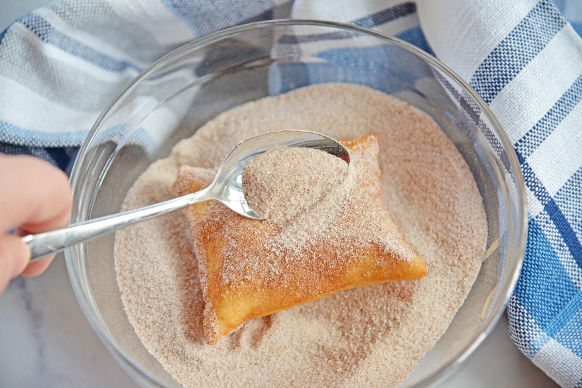 topping cinnamon sugar on a sopapilla 