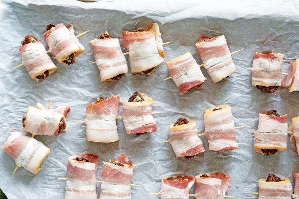 bacon wrapped dates on a baking sheet