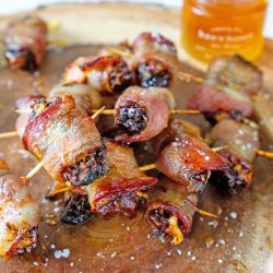 pile of bacon wrapped dates with pot of honey