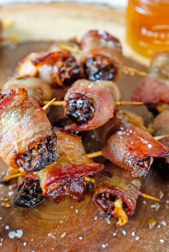 pile of bacon wrapped dates with pot of honey