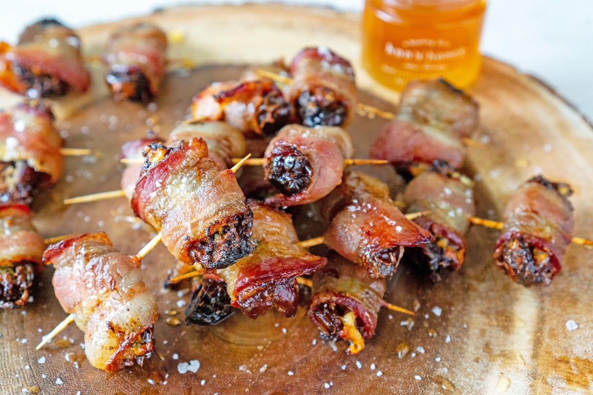 pile of bacon wrapped dates with pot of honey