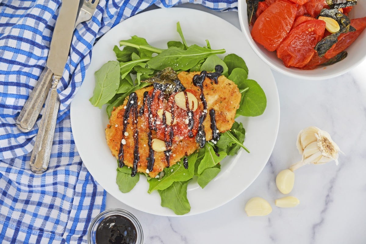 overhead of chicken cutlets with tomato garlic sauce on spinach