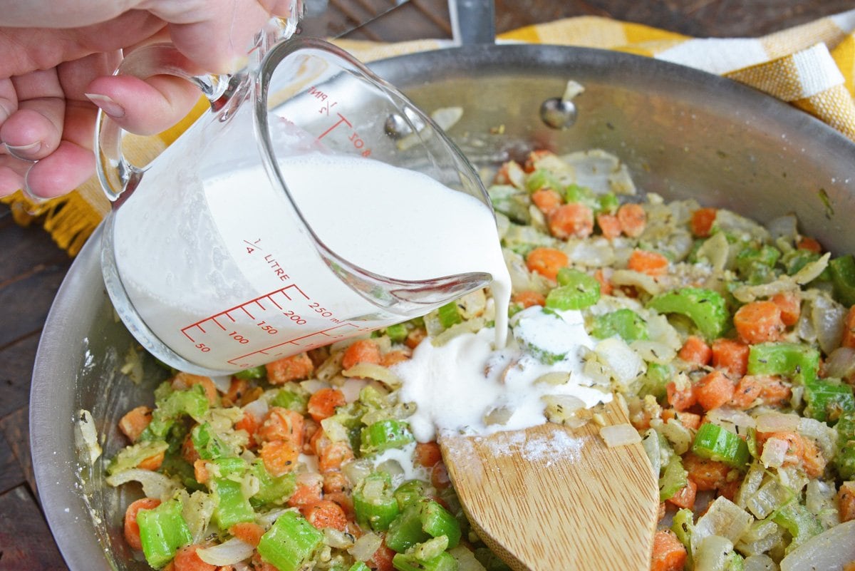 pouring cream into sauteed vegetables 