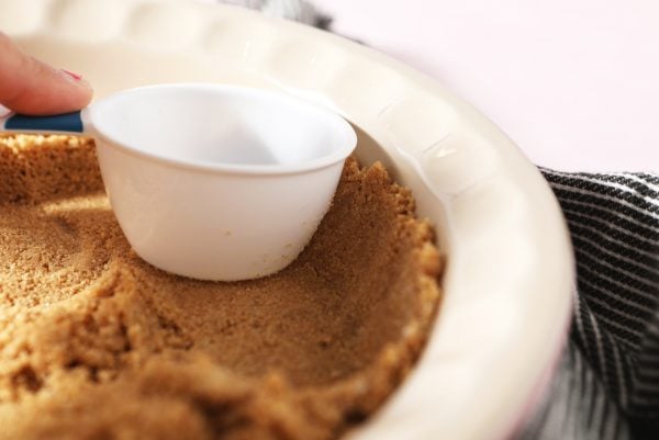 pressing graham cracker crust into a pie plate