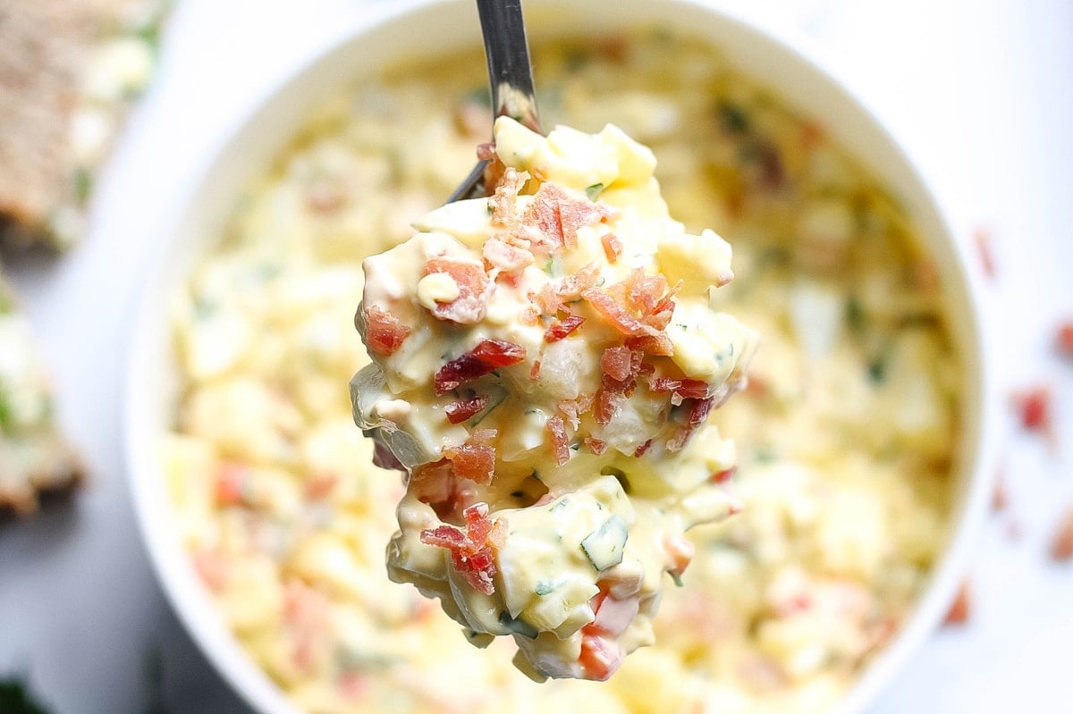 best egg salad recipe on a spoon with crumbled bacon 