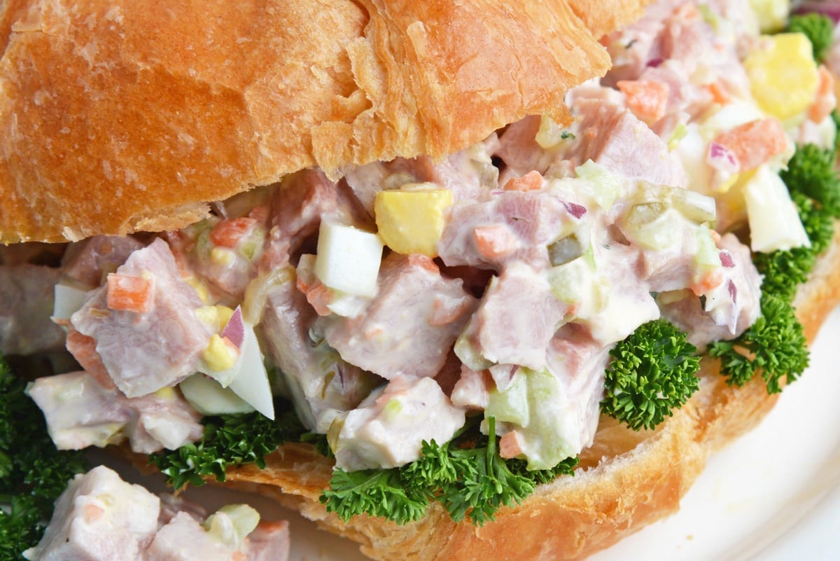 close up of chopped ham salad sandwich with greens 