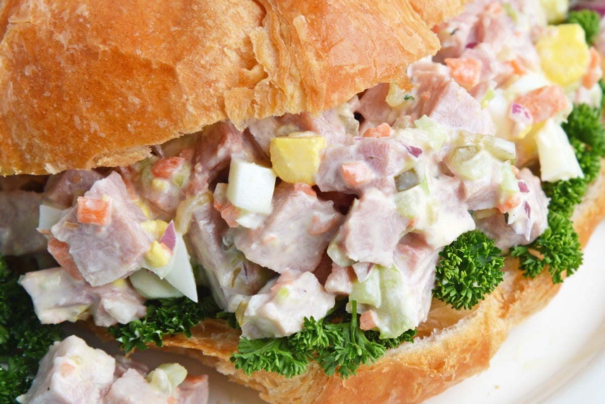 close up of chopped ham salad sandwich with greens 