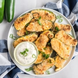 stuffed jalapenos on a serving dish with dip