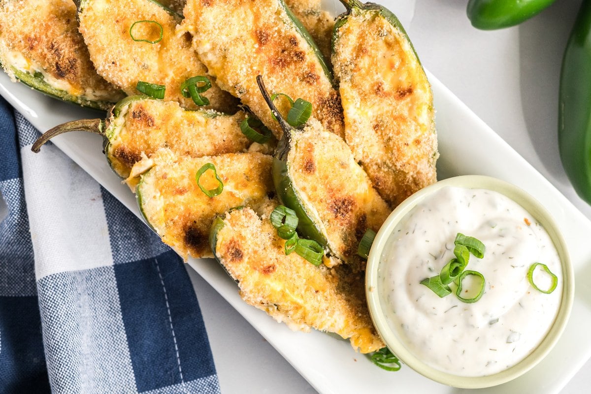stuffed jalapenos on a serving platter with dipping sauce  