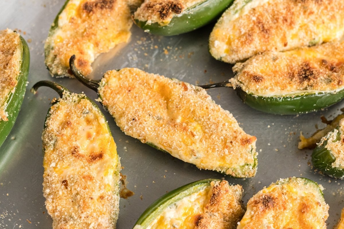 close up of jalapeno poppers with bacon on a baking sheet 