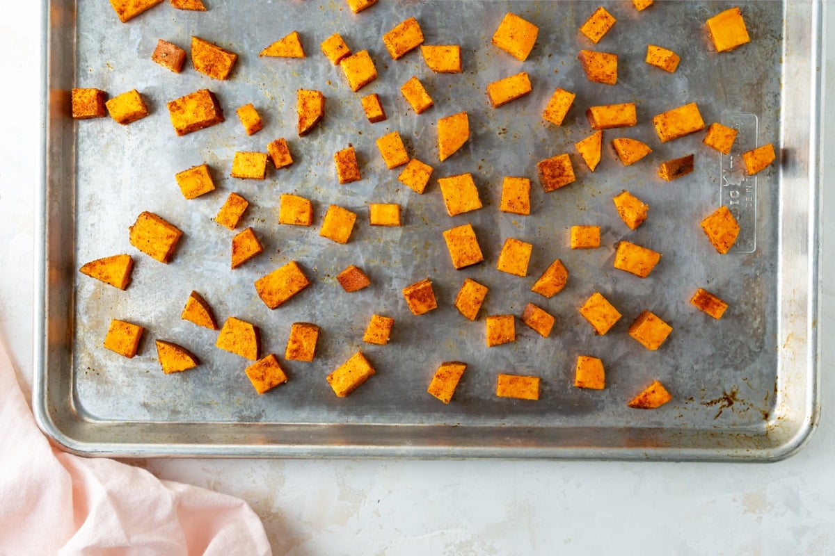 seasoned sweet potatoes on a sheet pan 