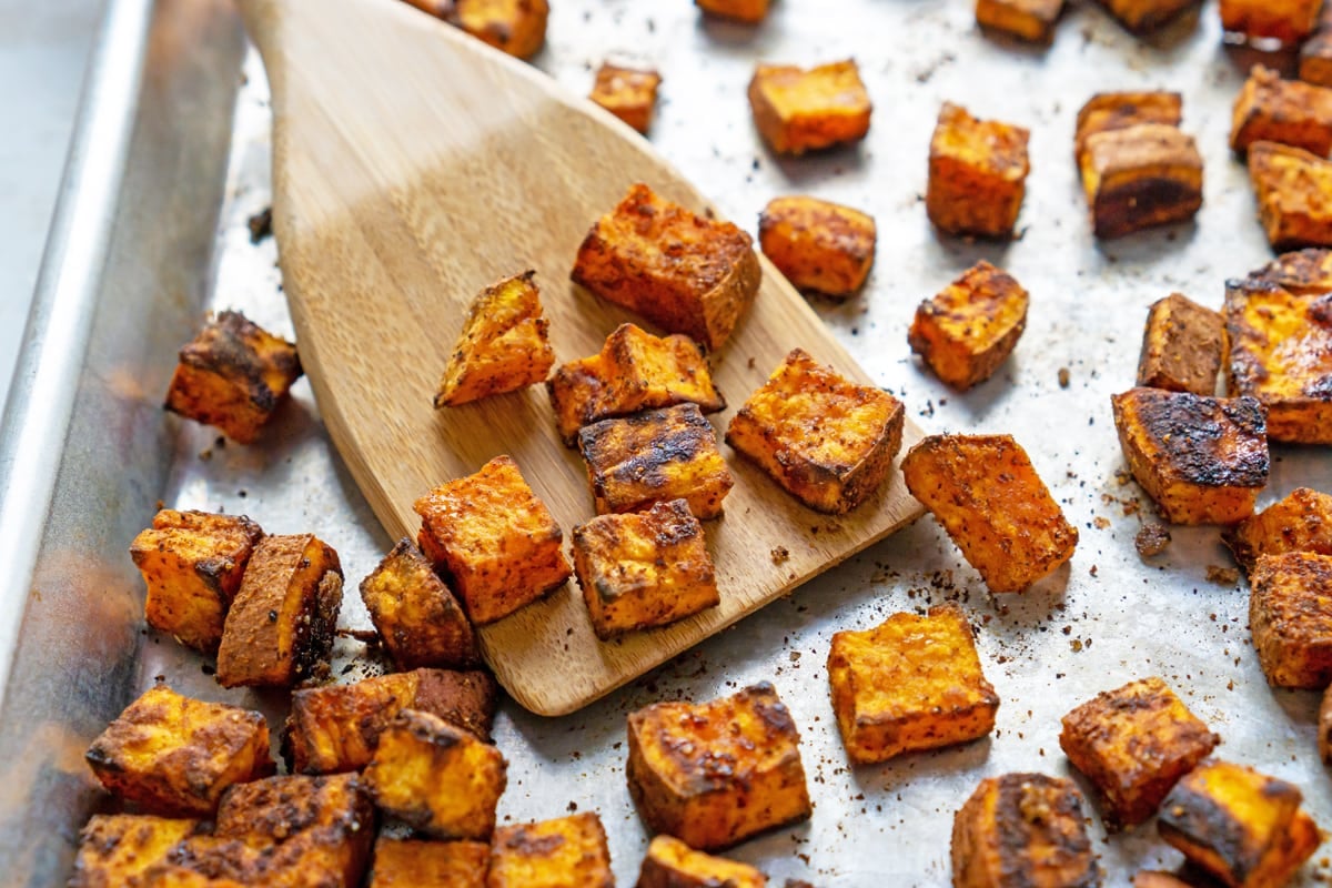 browned and crispy sweet potatoes on a rimmed baking sheet 