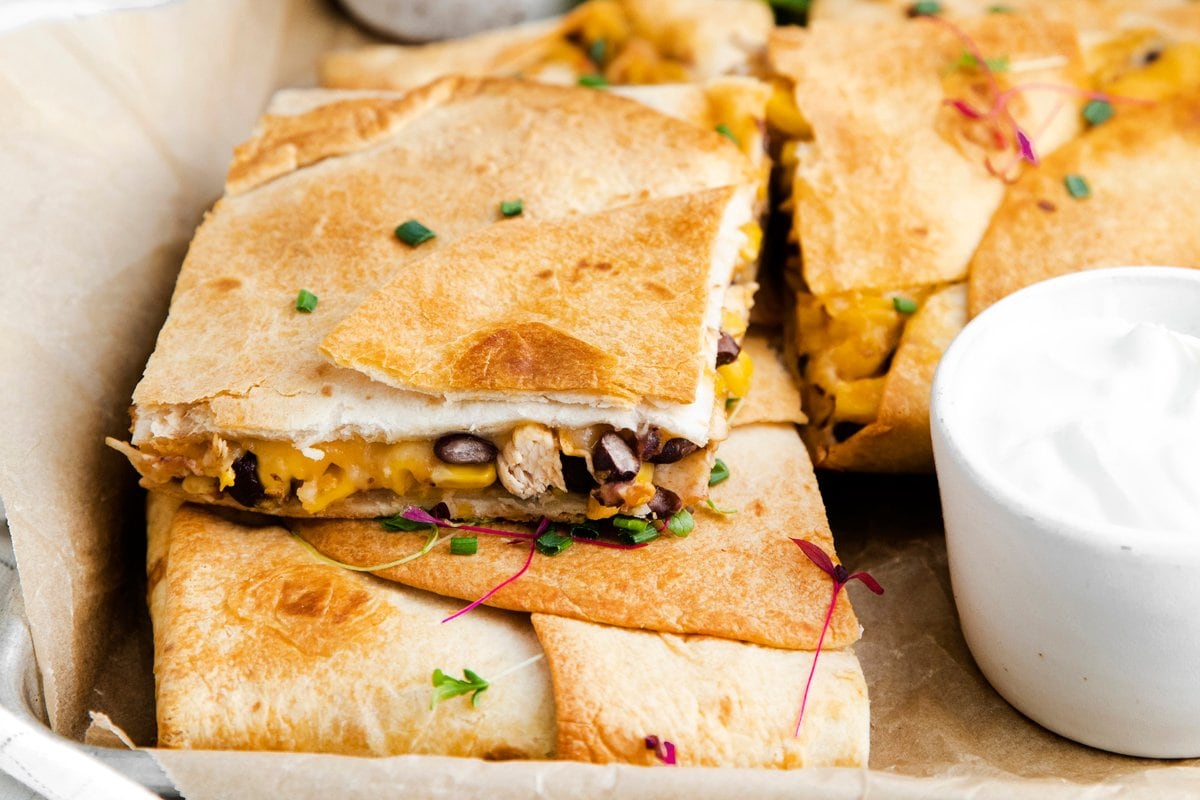 sheet pan quesadillas cut into wedges with corn, beans and cheese 