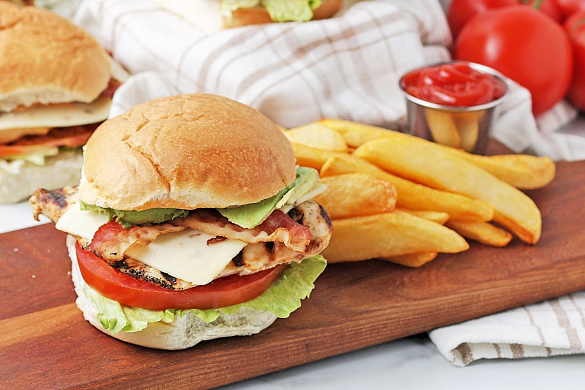 chicken sandwich on a wood board with fries 