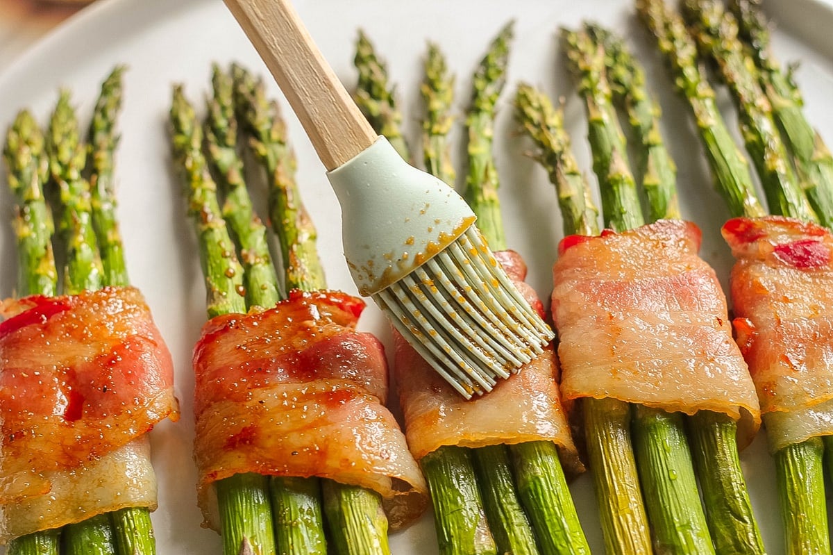 basting soy sauce blend over cooked bacon and asparagus 