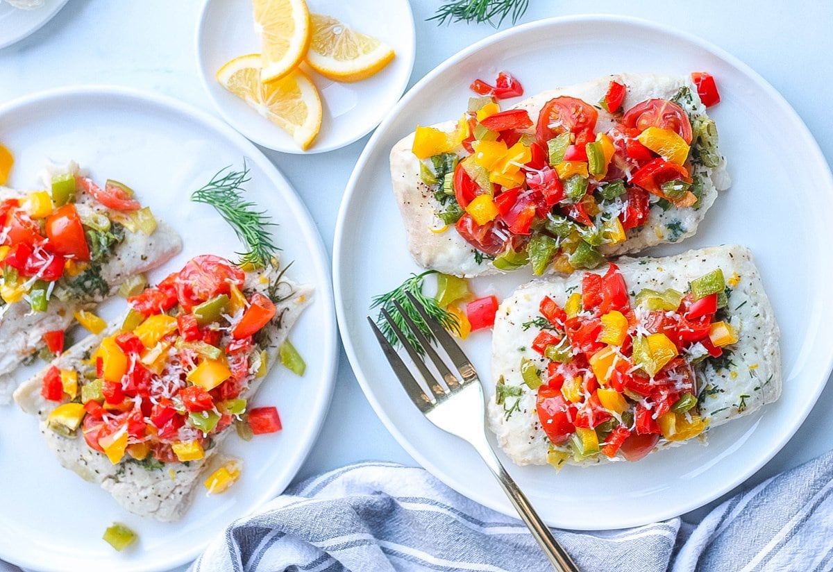 plated baked halibut topped with bell peppers, tomatoes and dill