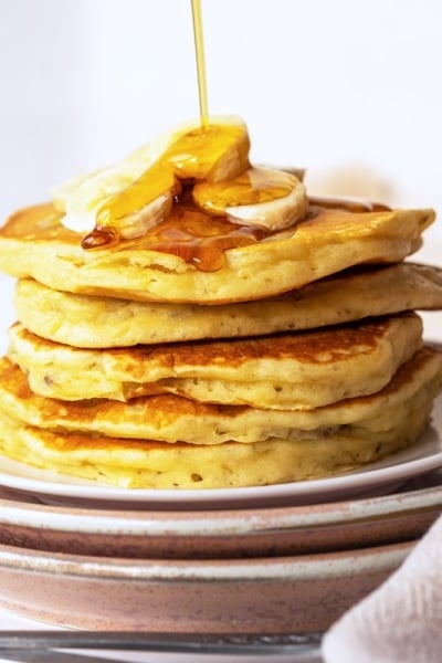 syrup pouring over a stack of banana pancakes