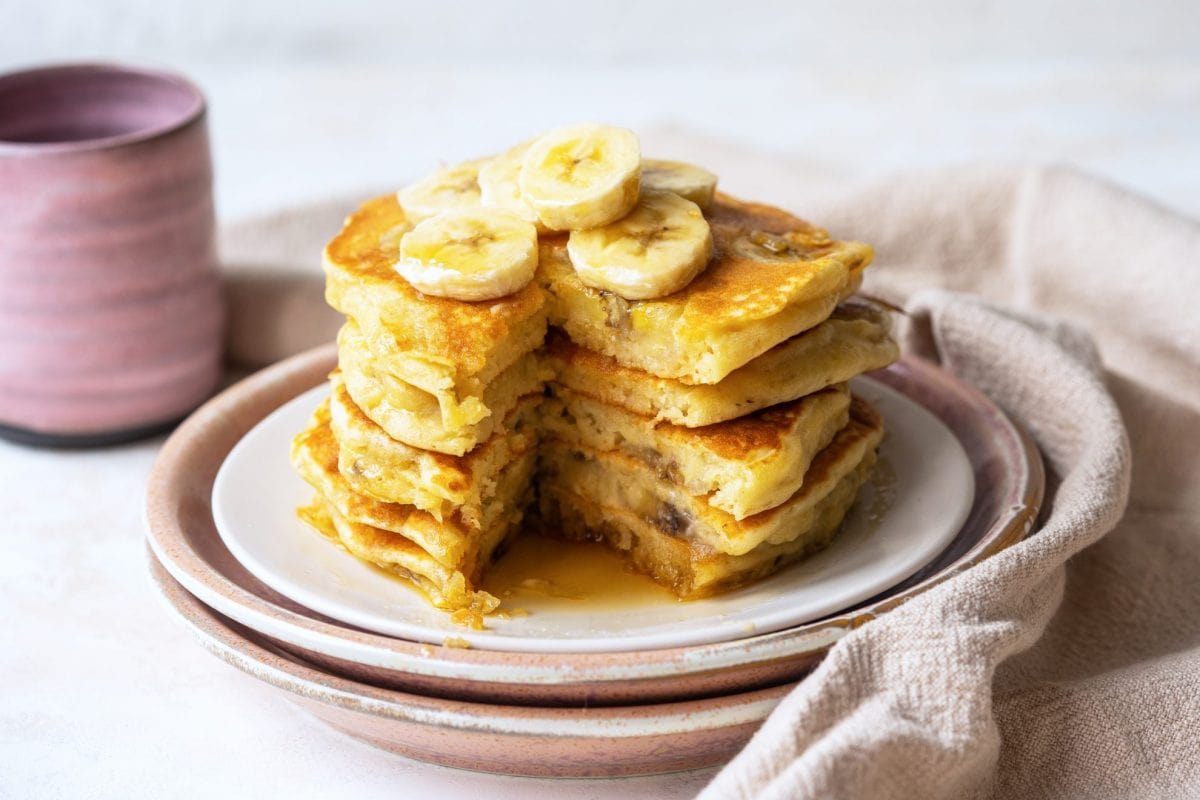 stack of banana pancakes with a big slice missing 