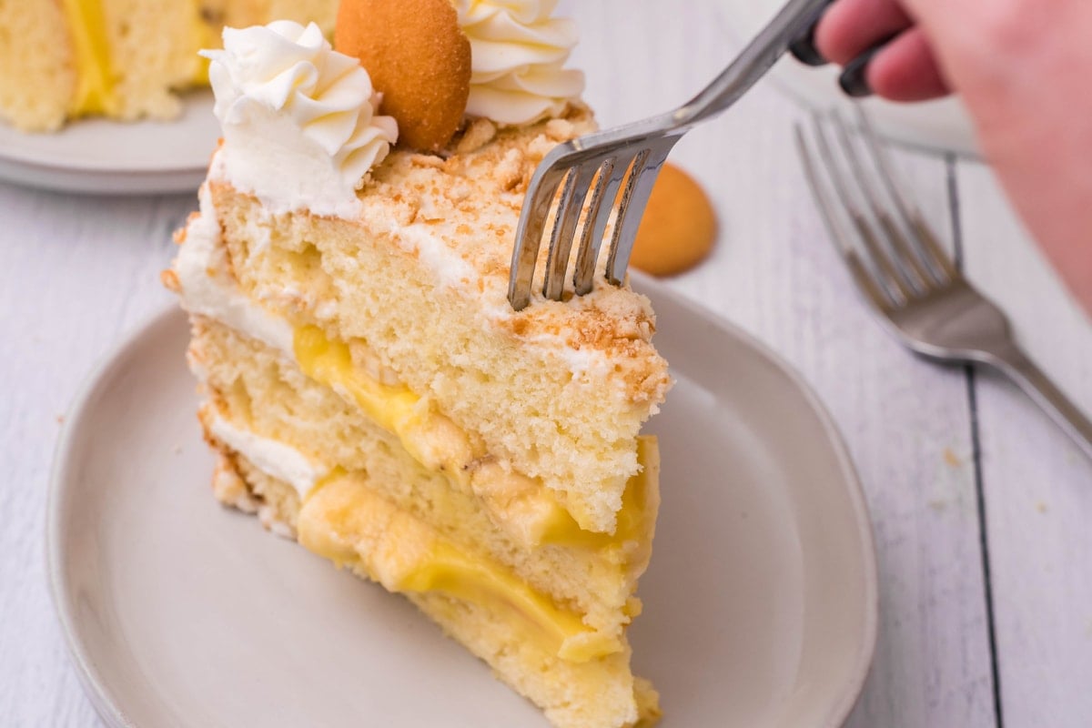 fork digging into a banana vanilla layer cake 