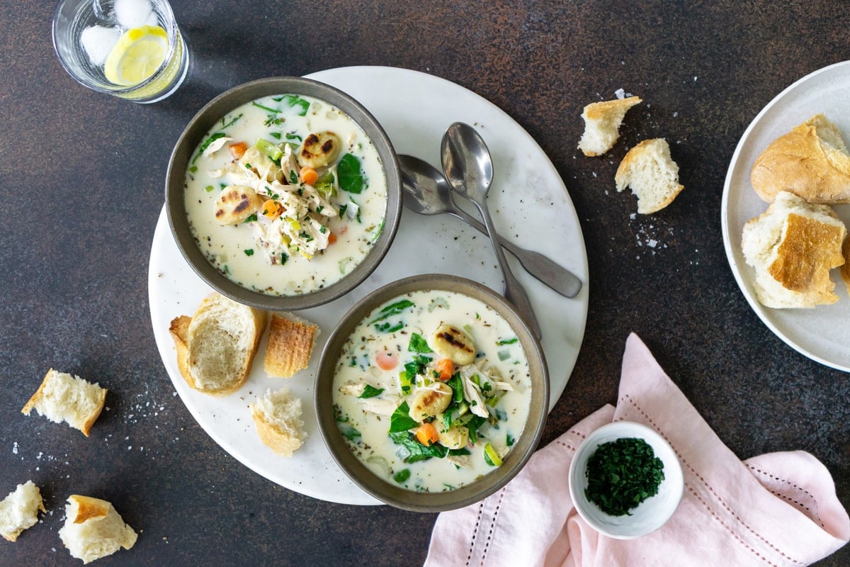 two bowls of chicken gnocchi soup on a serving platter