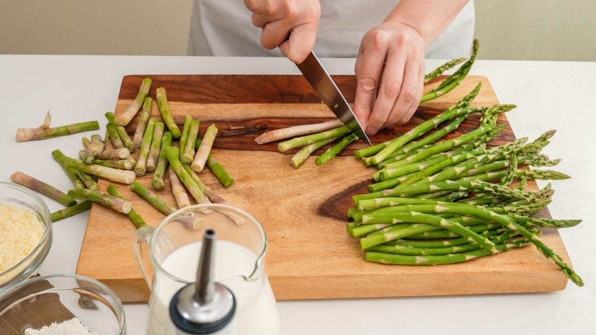 cutting asparagus on a wood cutting board 