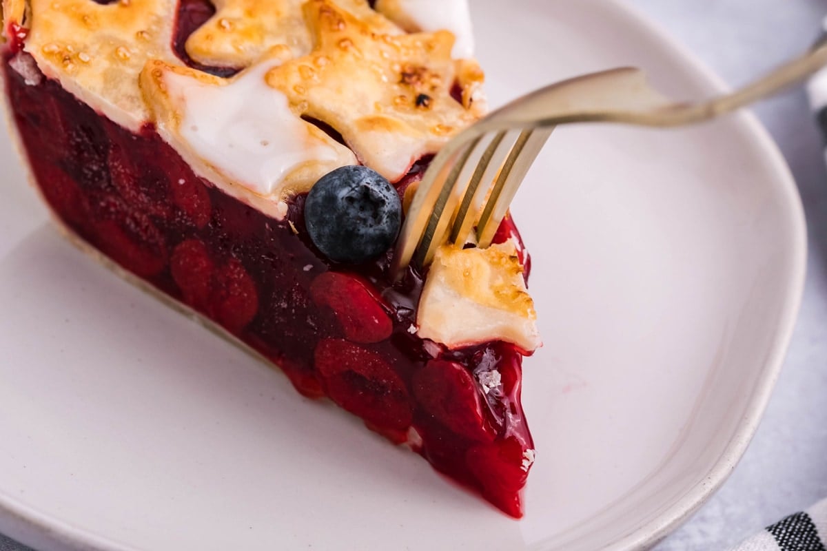 fork digging into a slice of cherry pie 