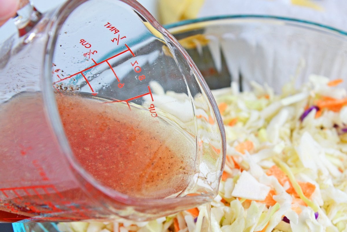 pouring vinegar dressing over coleslaw mix