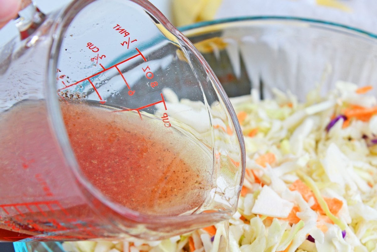 pouring vinegar dressing over coleslaw mix 