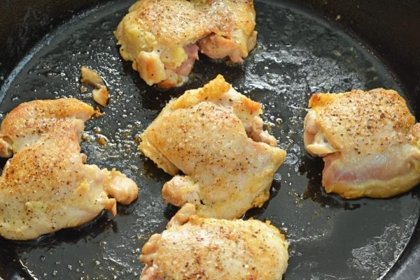 browned chicken thighs in a cast iron skillet