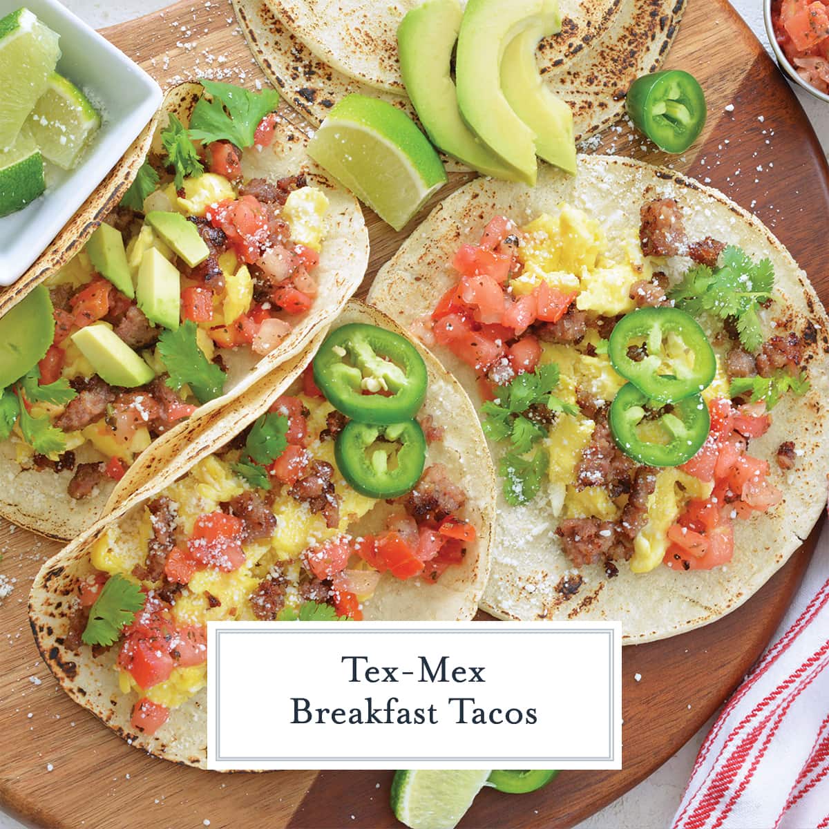 overhead of breakfast tacos on a wood board with toppings 