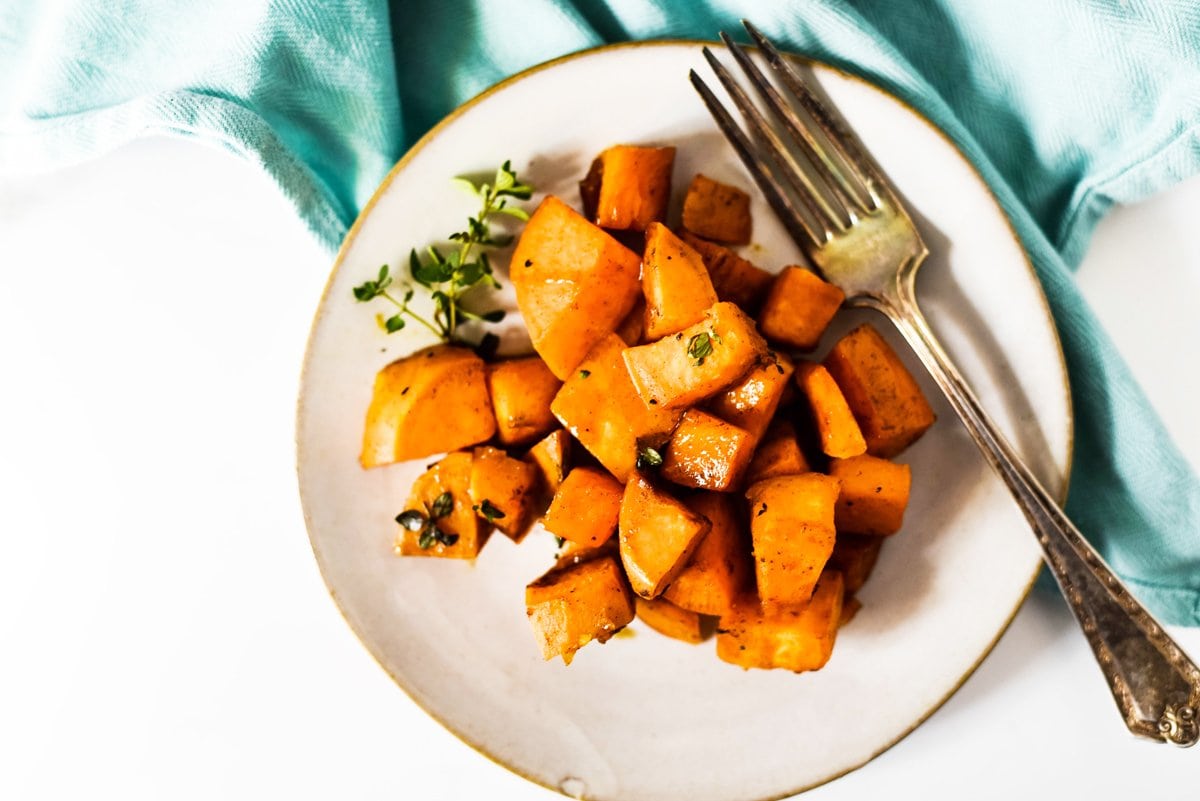 pan fried sweet potatoes on a small plate with a fork 