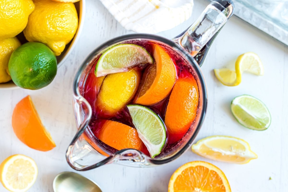 overhead of lemon, lime and orange in a pitcher with wine 