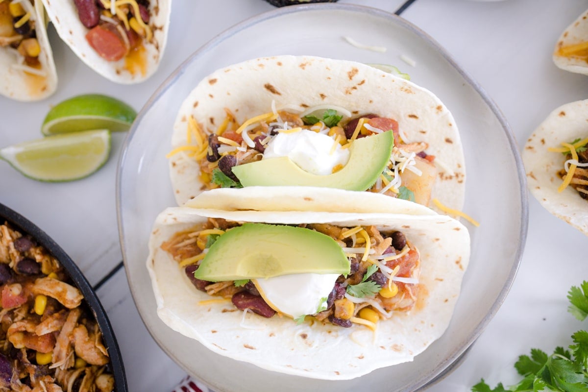 overhead of chicken soft tacos with avocado slice and cheese