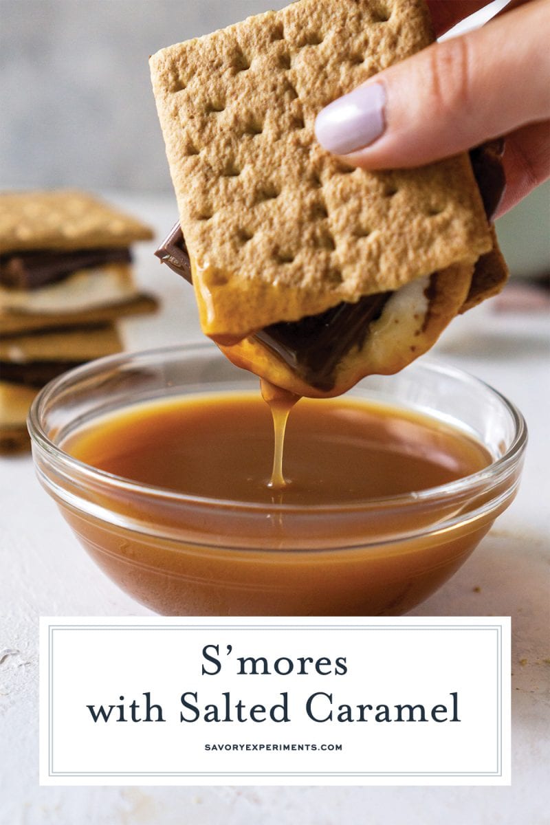 close up of hand dipping smore into caramel sauce 